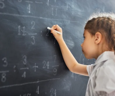 Holčička u tabule řeší matematický příklad.