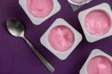 otevřené růžové jogurty, vedle nich lžička