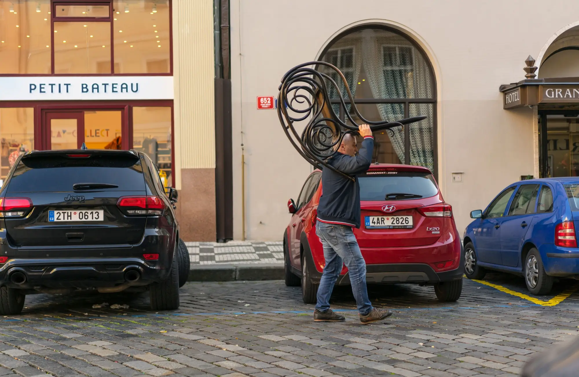 muž si nese houpací křeslo Thonet ulicí Prahy
