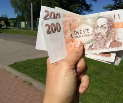 Člověk v ruce drží české bankovky.