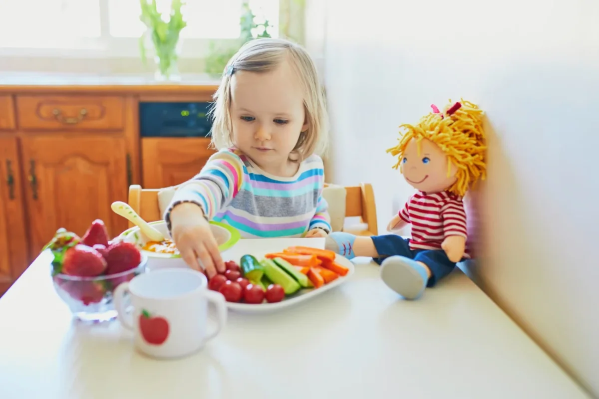 Dítě s talířem ovoce a zeleniny.