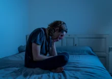 žena se krčí strachy na posteli