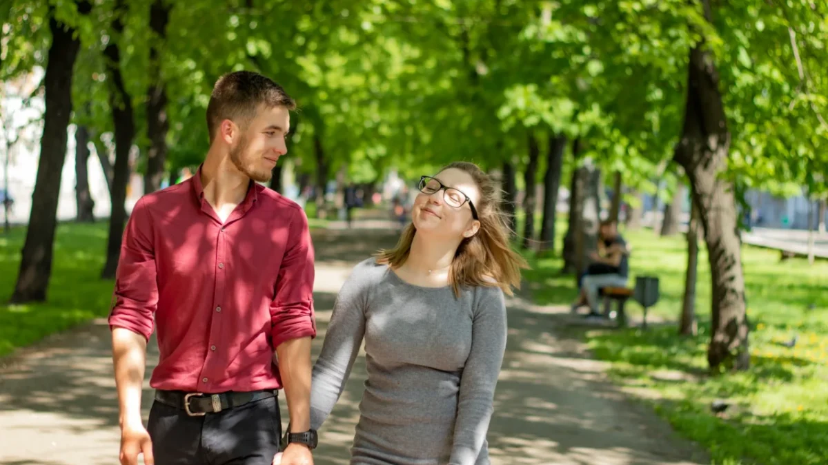 Žena s mužem se prochází mezi stromy.