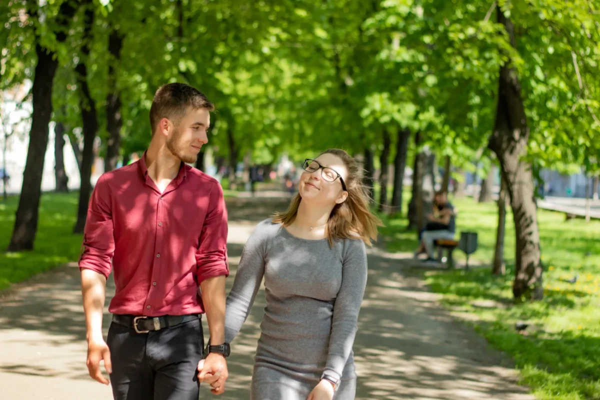 Žena s mužem se prochází mezi stromy.