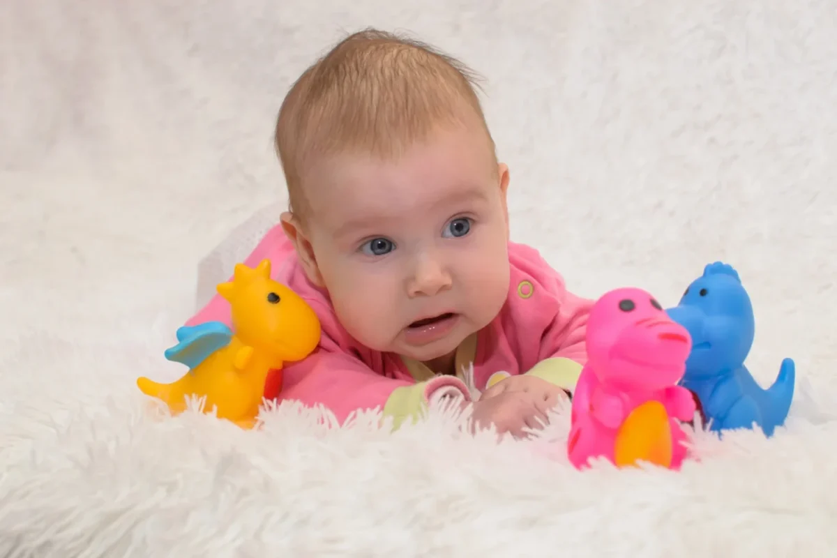 Miminko leží obklopené hračkami.