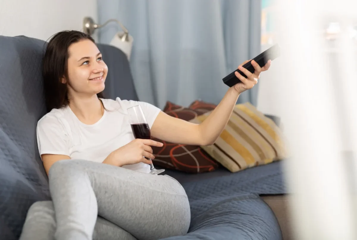 Žena míří ovladačem na televizi.