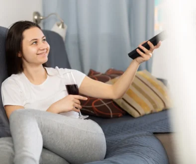 Žena míří ovladačem na televizi.