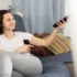 Žena míří ovladačem na televizi.