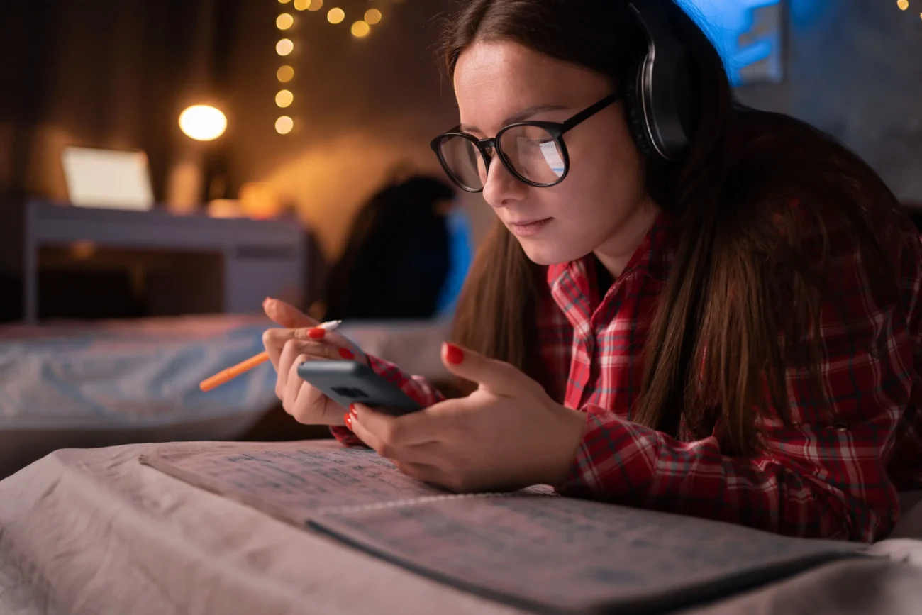 Telefon bychom měli odložit několik hodin před spaním. Zdroj: Shutterstock | TVGURU.cz Dívka s telefonem na posteli.