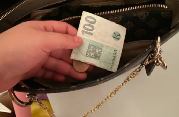 české koruny stokoruna drží ruka a dává do kabelky