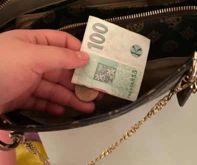 české koruny stokoruna drží ruka a dává do kabelky