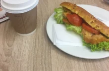 čerstvě připravený sendvič na stole vedle kávy v kelímku