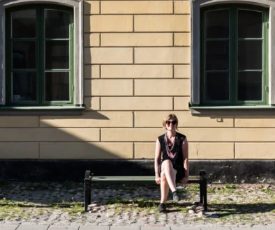 Žena sedí venku na lavičce.