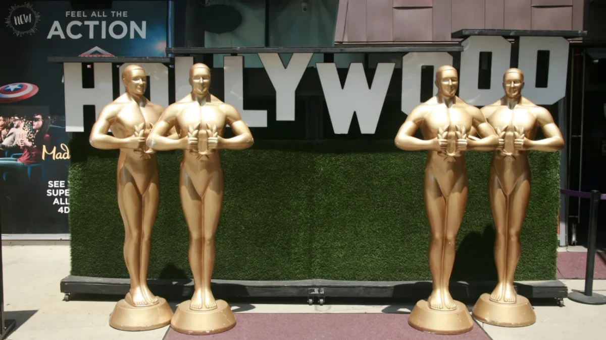 Velké sochy Oscara stojící u nápisu Hollywood.