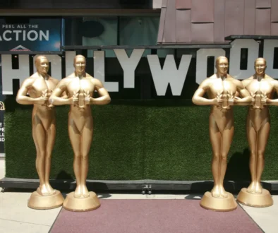 Velké sochy Oscara stojící u nápisu Hollywood.