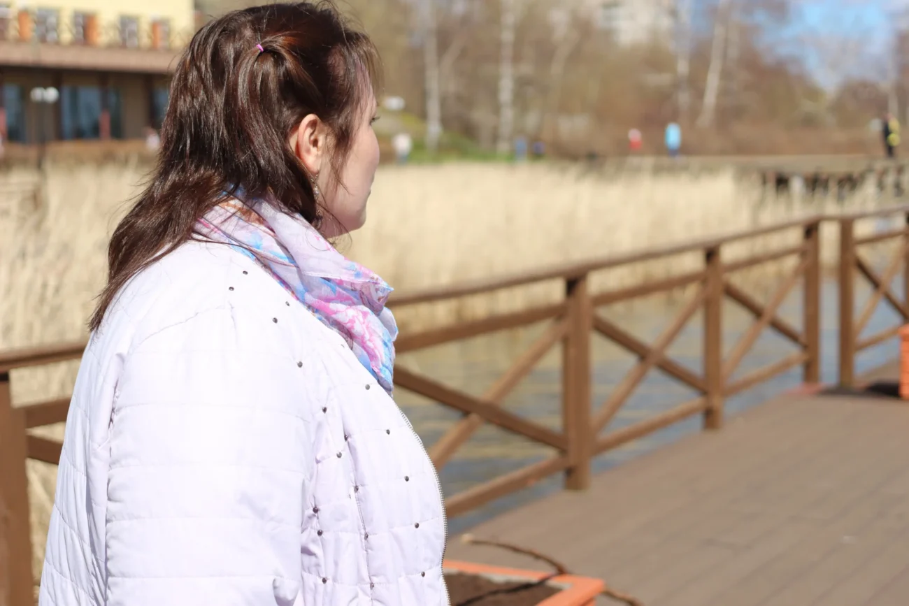 Žena s nadváhou je k nám otočená bokem a dívá se pryč.