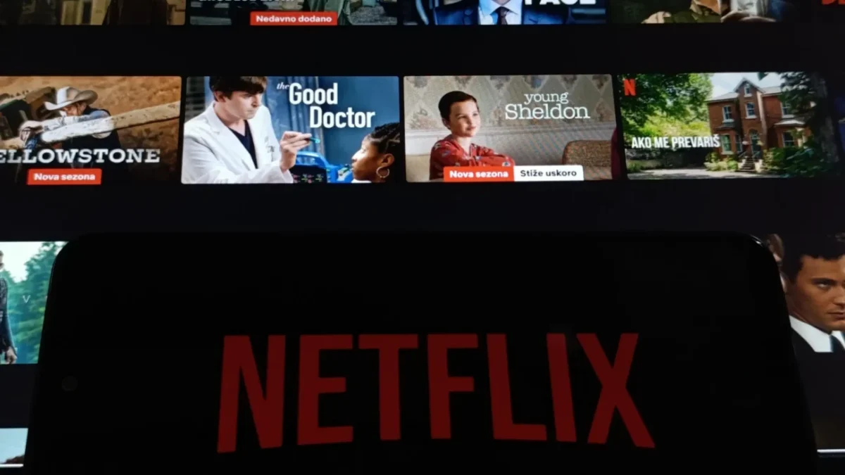 Netflix na telefonu a filmy v pozadí.