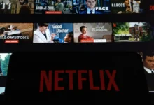 Netflix na telefonu a filmy v pozadí.