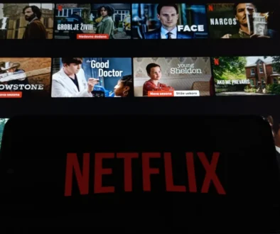 Netflix na telefonu a filmy v pozadí.