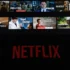 Netflix na telefonu a filmy v pozadí.