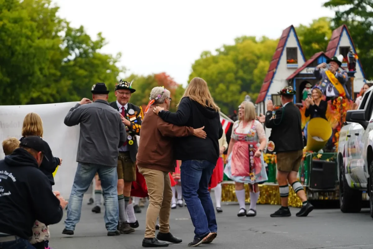 Lidé v krojích tancují na ulici.