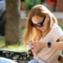 žena sedí na lavičce a dívá se do mobilu