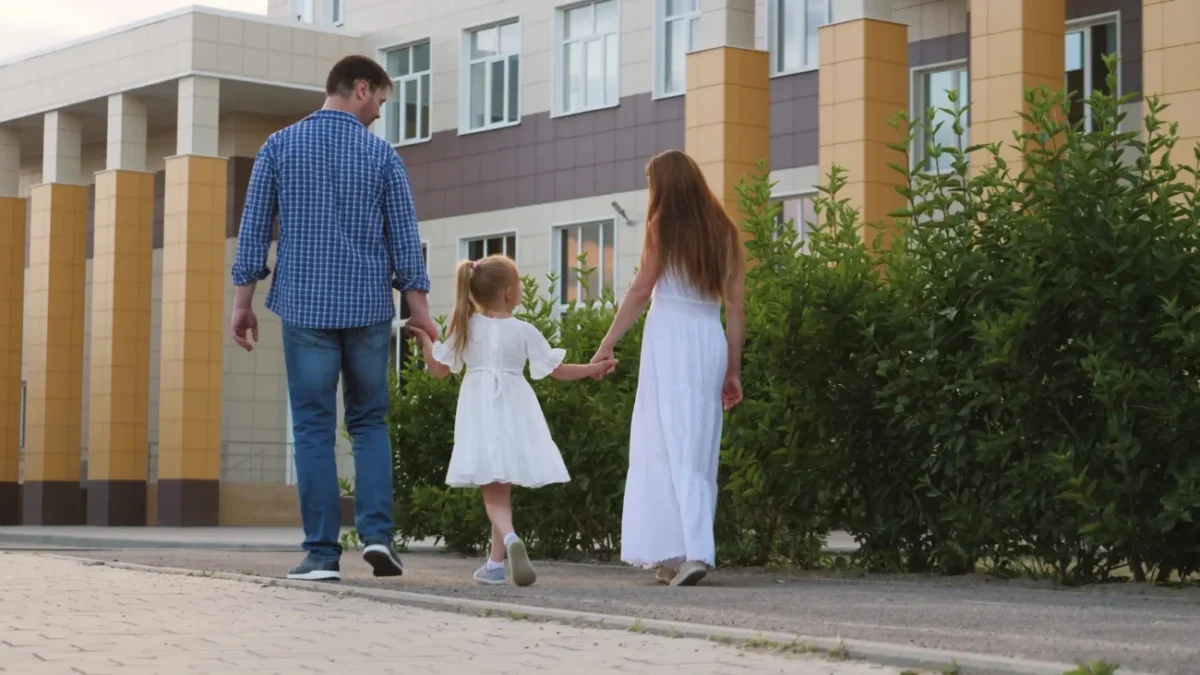 Muž s ženou drží za ruku holčičku a procházejí se venku.