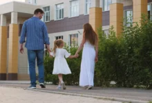 Muž s ženou drží za ruku holčičku a procházejí se venku.