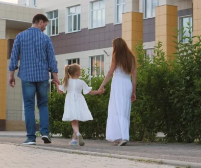 Muž s ženou drží za ruku holčičku a procházejí se venku.