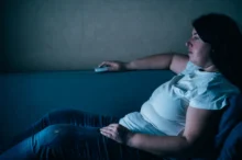 Žena leží na gauči.