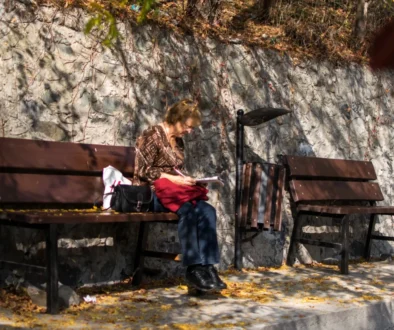 Babička sedí na lavičce a lušti křížovku.