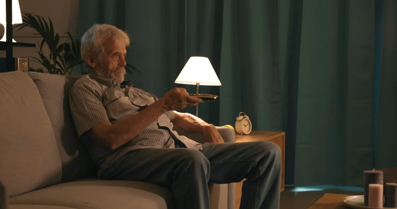 Senior sám sedící na gauči.