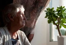 Osamocená seniorka dívající se z okna.