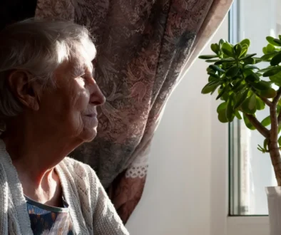 Osamocená seniorka dívající se z okna.