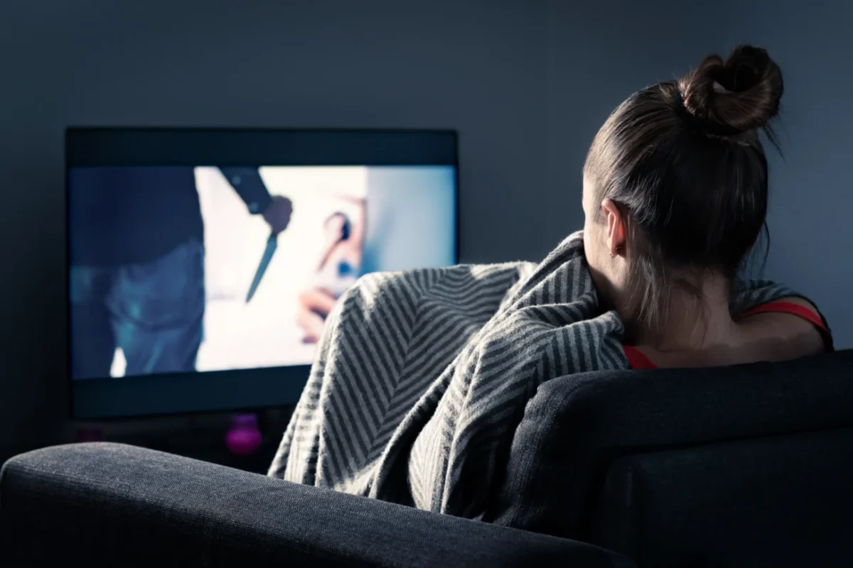 Žena se dívá na strašidelný pořad v televizi.