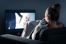 Žena se dívá na strašidelný pořad v televizi.