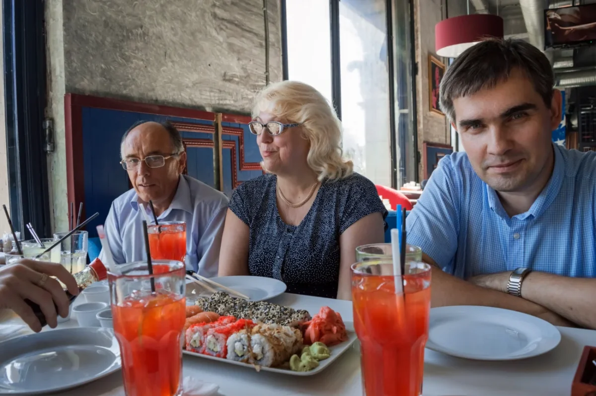 Lidé sedí u stolu, na kterém je spousta jídla.