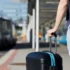 Muž stojí u autobusové zastávky s kufrem.