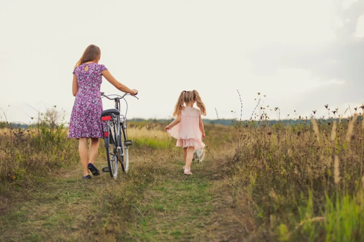 Žena s holčičkou kráčí po polní cestě.