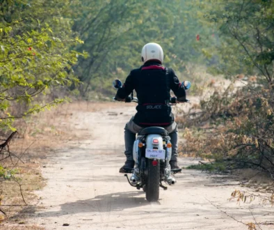 Muž jedoucí na motorce lesní cestou.