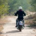 Muž jedoucí na motorce lesní cestou.