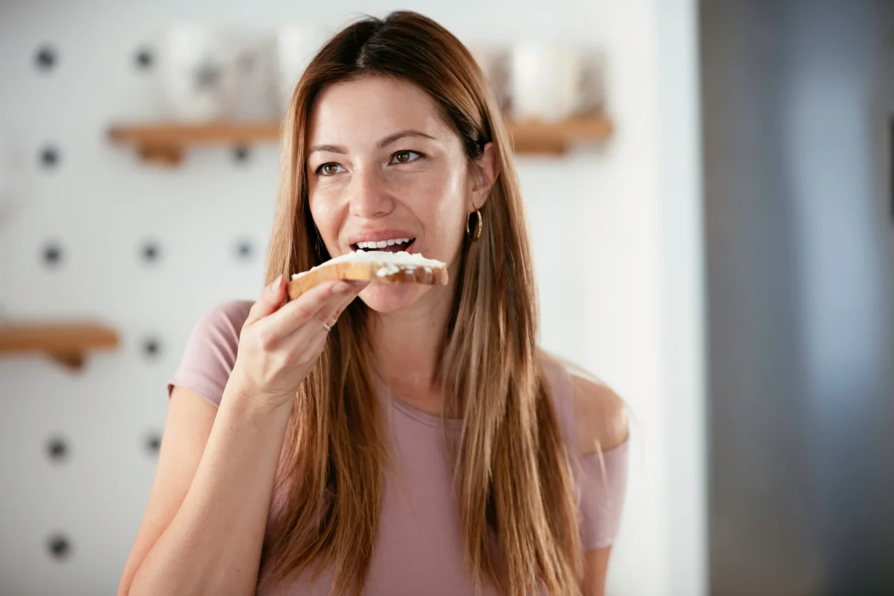 Připravit si lze i vlastní pomazánky. Zdroj: Shutterstock | TVGURU.cz Dívka, která jí namazaný chleba.
