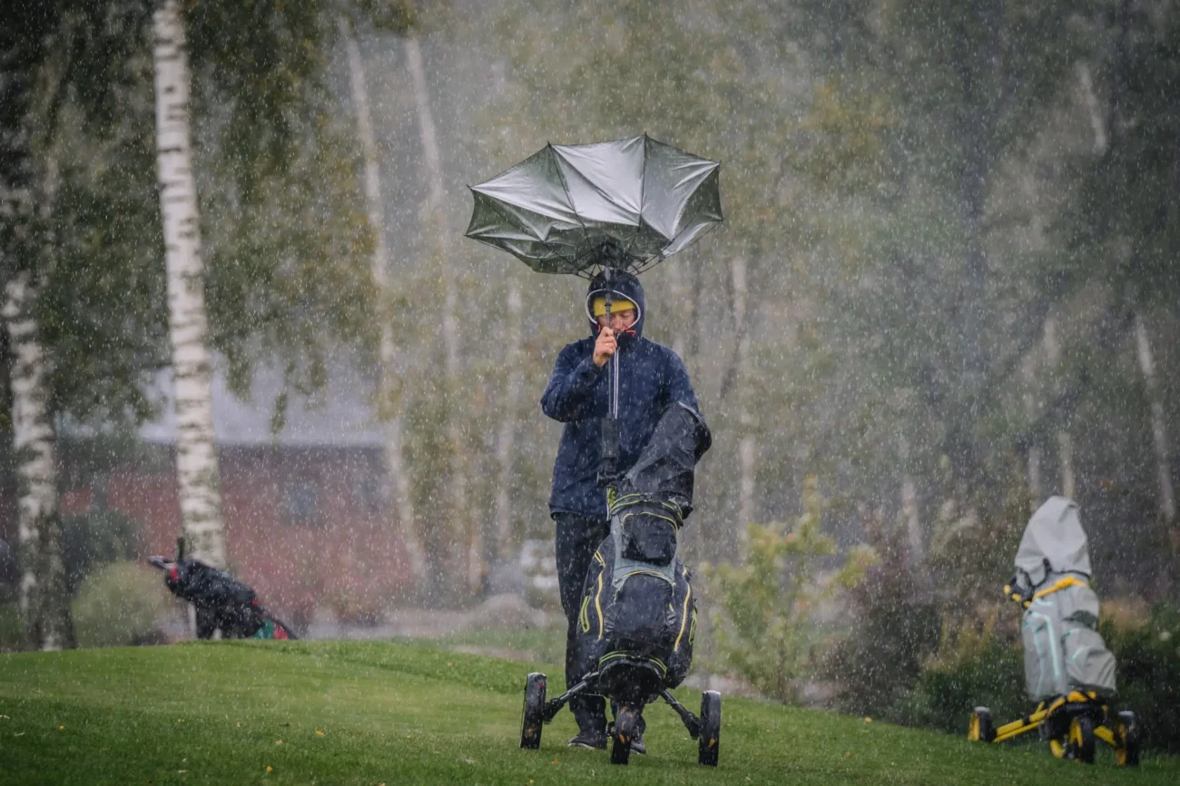 Muž hraje golf v dešti. 