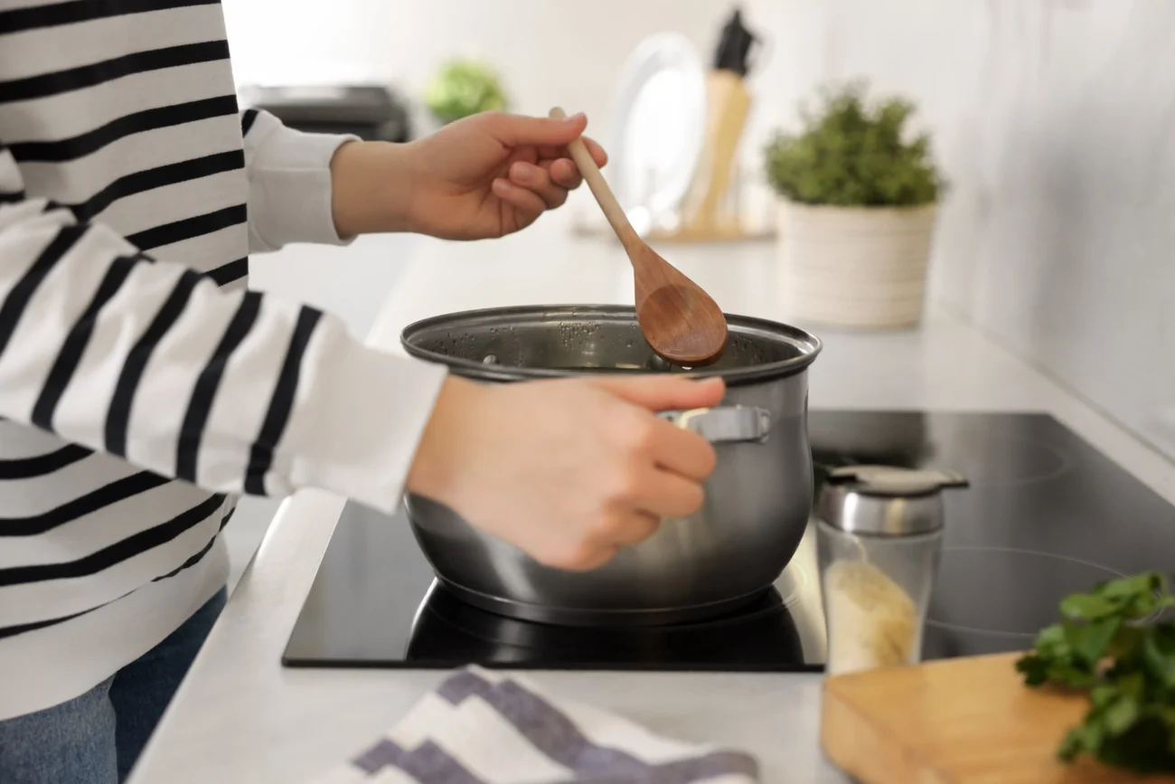 Příprava tohoto pokrmu trvá jen pár minut. Z jeho chuti ale cizinci nadšení nejsou. Zdroj: Shutterstock | TVGURU.cz Ruce míchající vařečkou v hrnci.