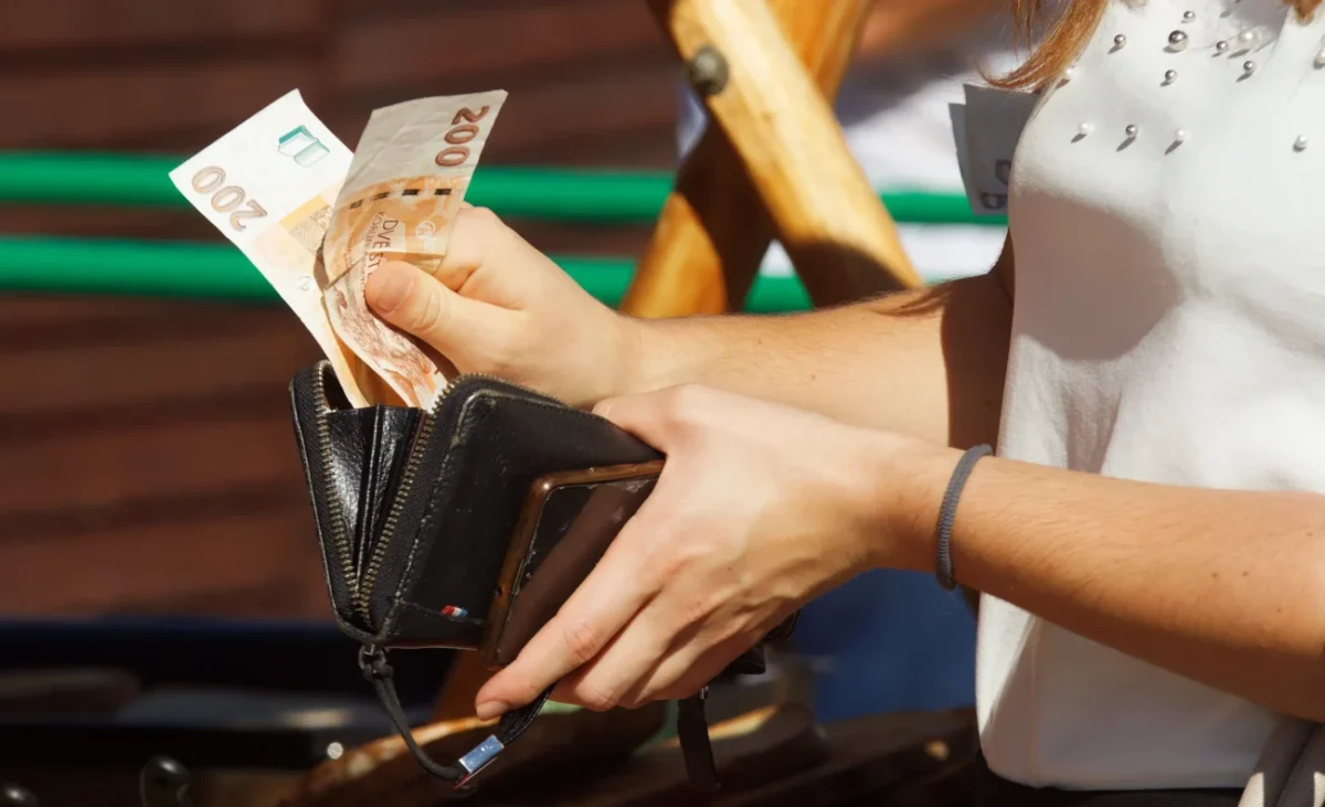 Žena si z peněženky vyndavá peníze.
