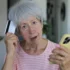 Starší žena v ruce drží telefon a platební kartu.