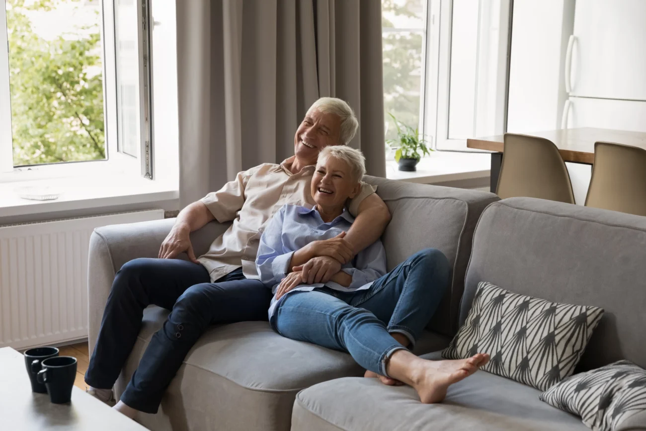 Lidé se u televize smáli ještě před tím, než herec promluvil. Zdroj: Shutterstock | TVGURU.cz Senioři ležící na gauči a dívající se na televizi.