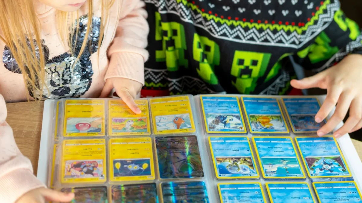 Dva školáci (dívka a chlapec) si společně prohlížejí album Pokémonů