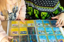 Dva školáci (dívka a chlapec) si společně prohlížejí album Pokémonů