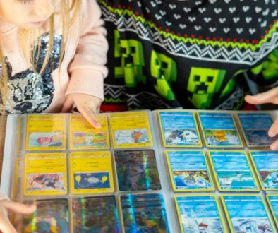 Dva školáci (dívka a chlapec) si společně prohlížejí album Pokémonů